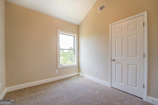 carpeted empty room with lofted ceiling and baseboards