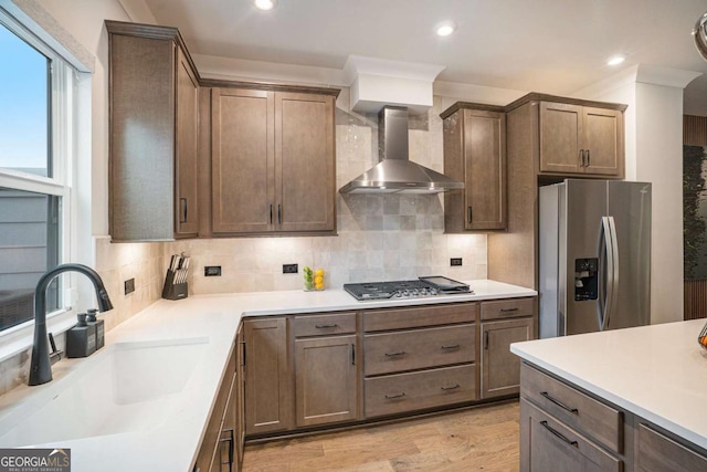2505 Astaire Ct NW, Atlanta, GA 30318 - kitchen featuring appliances with stainless steel finishes, wall chimney range hood, a sink, decorative backsplash, and light wood-style flooring