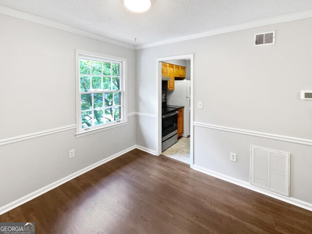 unfurnished room with wood finished floors, ornamental molding, a textured ceiling, and baseboards