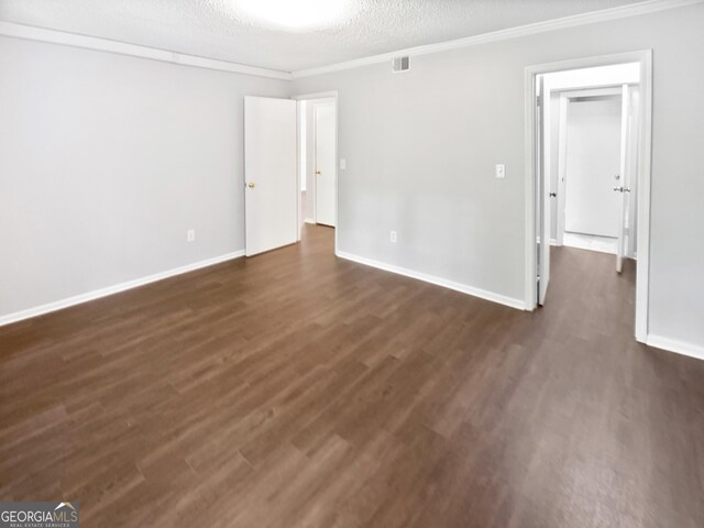 unfurnished room featuring dark wood finished floors, baseboards, ornamental molding, and a textured ceiling