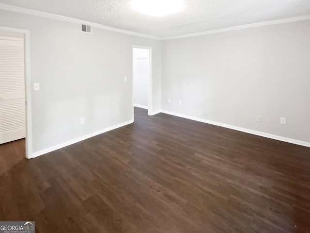 empty room featuring ornamental molding, dark wood-style flooring, baseboards, and a textured ceiling
