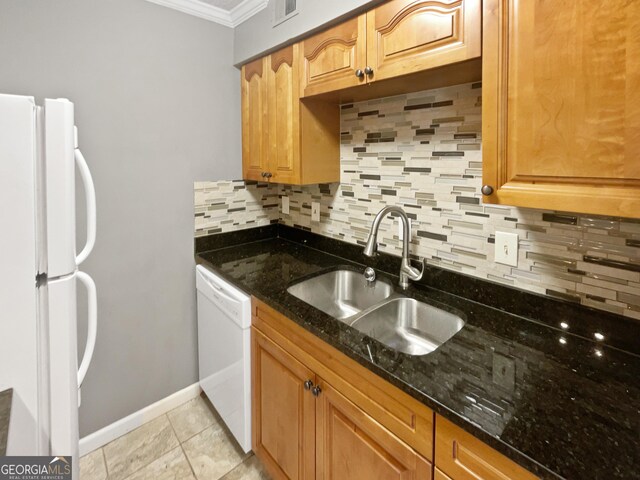 kitchen featuring white appliances, a sink, decorative backsplash, ornamental molding, and dark stone counters