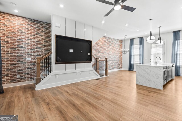 4462 Dandelion Ln, Atlanta, GA 30342 - unfurnished living room featuring brick wall, a sink, light wood-style flooring, ceiling fan, and baseboards