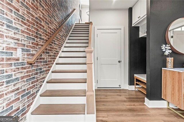 4462 Dandelion Ln, Atlanta, GA 30342 - stairway featuring wood finished floors and brick wall