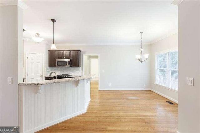 5065 Hickory Hills Dr, Woodstock, GA 30188 - kitchen with stainless steel microwave, a kitchen bar, dark brown cabinetry, tasteful backsplash, and light wood finished floors
