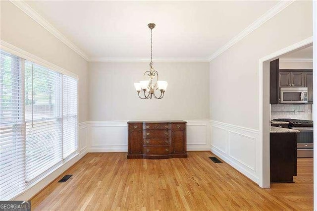 5065 Hickory Hills Dr, Woodstock, GA 30188 - unfurnished dining area featuring a chandelier, light wood-style floors, crown molding, and wainscoting