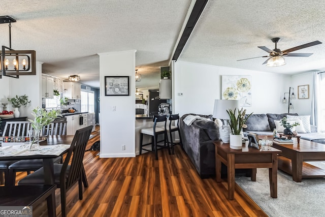 living area with dark wood-style floors, a textured ceiling, a ceiling fan, and a chandelier