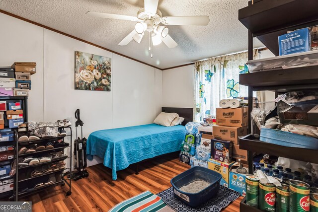 bedroom with a textured ceiling, wood finished floors, ornamental molding, and a ceiling fan