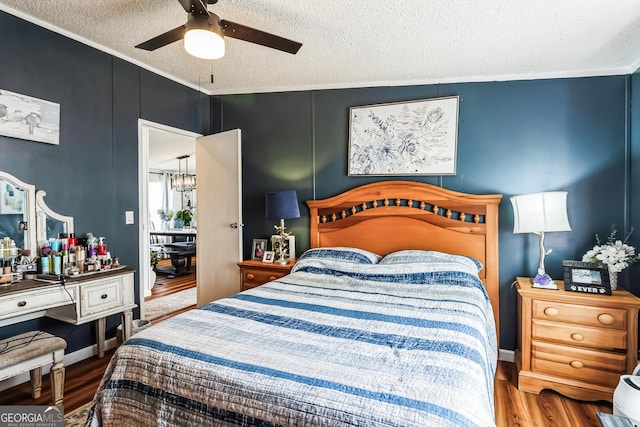 bedroom featuring wood finished floors, a textured ceiling, ceiling fan, and a chandelier