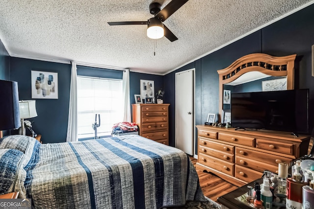 bedroom with a textured ceiling, wood finished floors, crown molding, and a ceiling fan