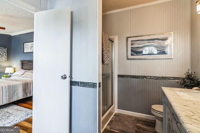 full bath featuring a textured ceiling, ornamental molding, ensuite bathroom, a shower stall, and wood finished floors