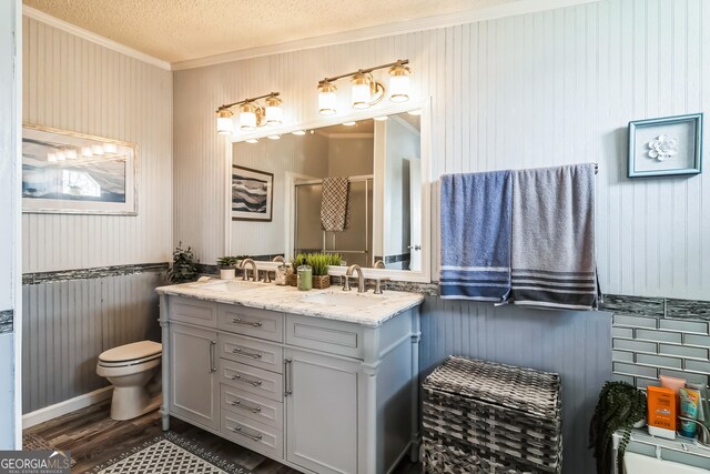 bathroom featuring crown molding, toilet, double vanity, a textured ceiling, and wainscoting