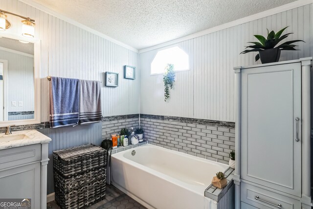 bathroom with ornamental molding, a textured ceiling, vanity, and a garden tub