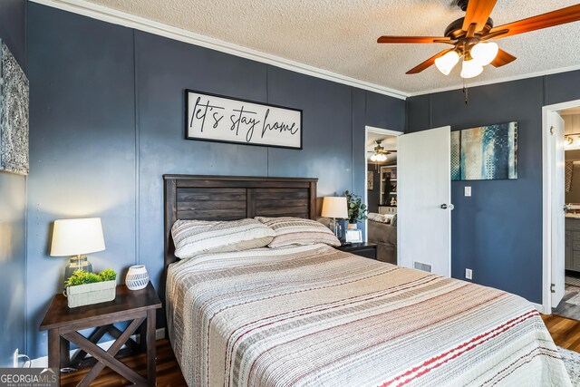 bedroom with wood finished floors, a textured ceiling, ornamental molding, ensuite bathroom, and a ceiling fan