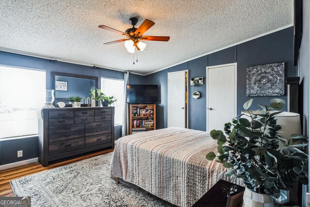 bedroom featuring wood finished floors, ornamental molding, a textured ceiling, and ceiling fan