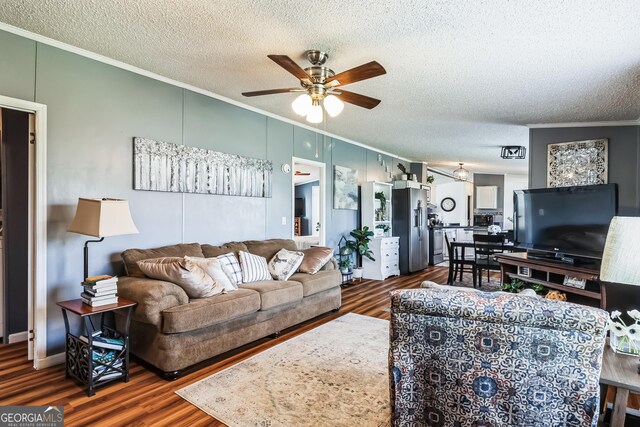 living room with ornamental molding, wood finished floors, ceiling fan, and a textured ceiling