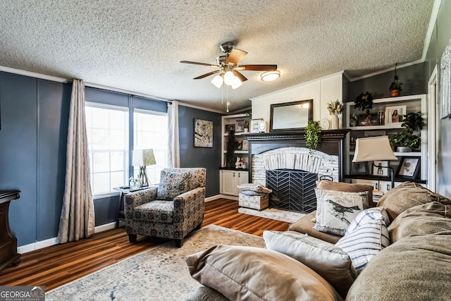 living area with ornamental molding, a fireplace, wood finished floors, and ceiling fan