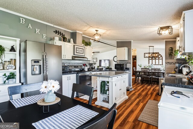 kitchen with stainless steel appliances, a sink, a textured ceiling, white cabinetry, and dark countertops