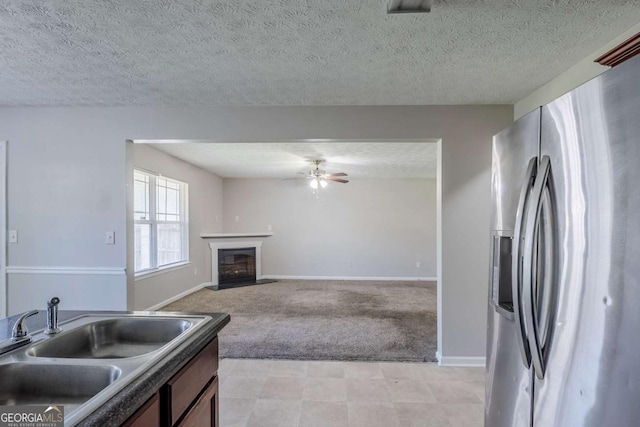 1436 Arbor Place Dr, Morrow, GA 30260 - kitchen with stainless steel refrigerator with ice dispenser, a sink, light colored carpet, a ceiling fan, and a glass covered fireplace