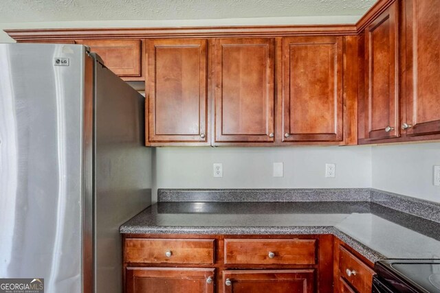 1436 Arbor Place Dr, Morrow, GA 30260 - kitchen featuring freestanding refrigerator, dark countertops, brown cabinets, and black range with electric stovetop