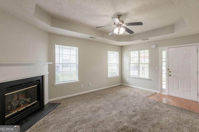 3531 Brookstone Way, Union City, GA 30291 - unfurnished living room featuring a tray ceiling, a textured ceiling, carpet floors, a ceiling fan, and a glass covered fireplace