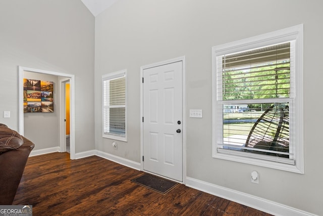 entrance foyer with dark wood-style flooring, baseboards, healthy amount of natural light, and high vaulted ceiling