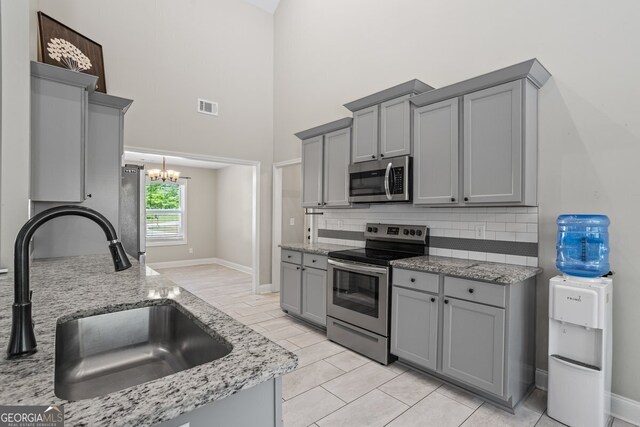 121 Bob Cat Trl, Mansfield, GA 30055 - kitchen featuring appliances with stainless steel finishes, gray cabinets, a sink, a towering ceiling, and a chandelier