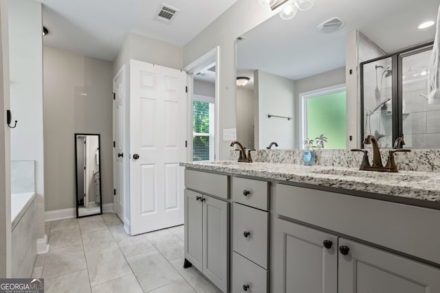 bathroom featuring a stall shower, double vanity, a bathtub, and baseboards