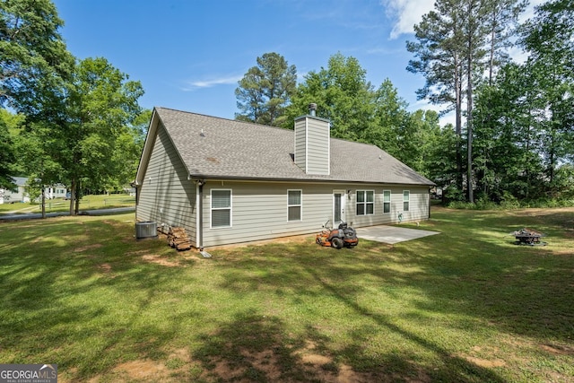 rear view of house with an outdoor fire pit, a patio area, a yard, central AC, and a chimney