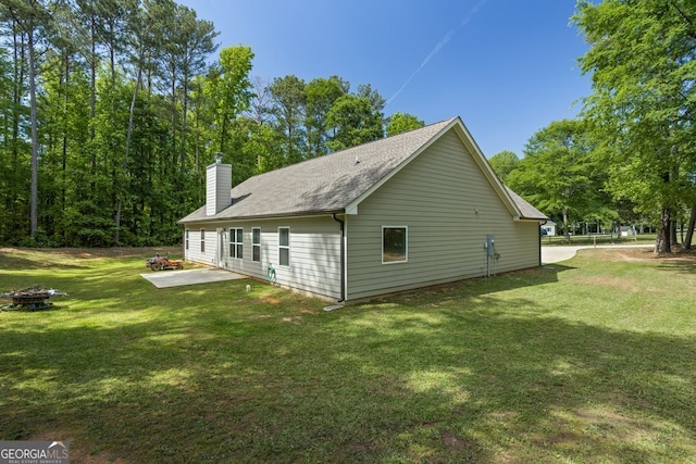 121 Bob Cat Trl, Mansfield, GA 30055 - view of side of property with a fire pit, a patio area, a lawn, a chimney, and a shingled roof