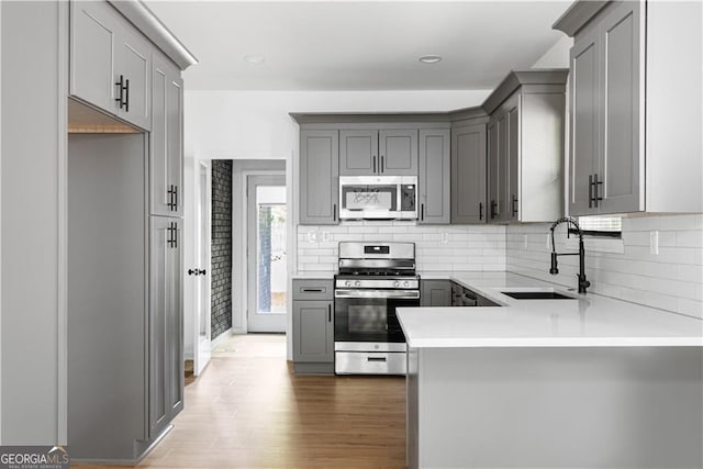 994 Byron Dr SW, Atlanta, GA 30310 - kitchen featuring stainless steel appliances, a sink, gray cabinetry, decorative backsplash, and wood finished floors