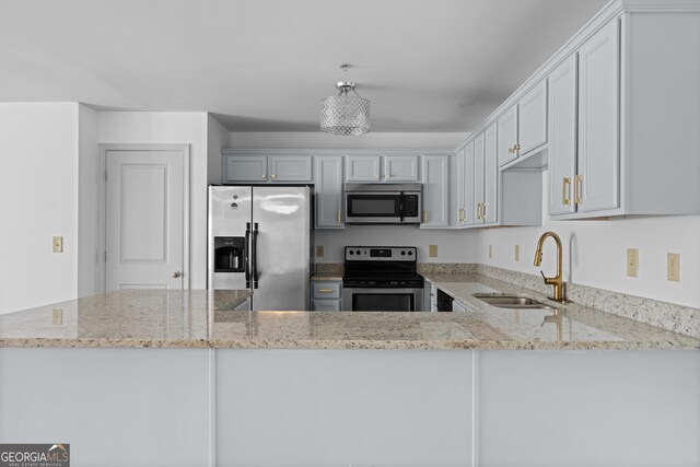 1102 Madison Ln SE, Smyrna, GA 30080 - kitchen featuring appliances with stainless steel finishes, a sink, light stone countertops, and a peninsula