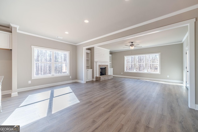 unfurnished living room featuring baseboards, light wood finished floors, crown molding, a fireplace, and a ceiling fan