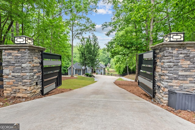 gate featuring fence and view of wooded area