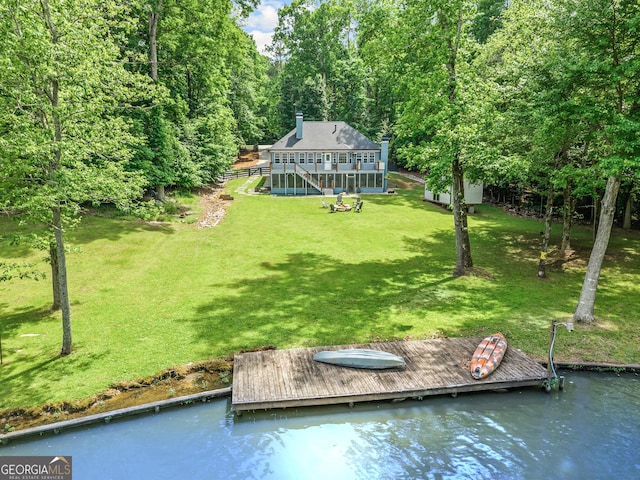back of house featuring stairway, a lawn, and a water view