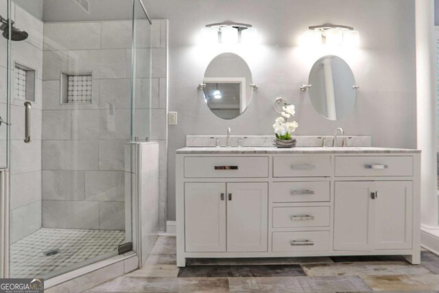 full bath featuring a stall shower, double vanity, and wood finished floors