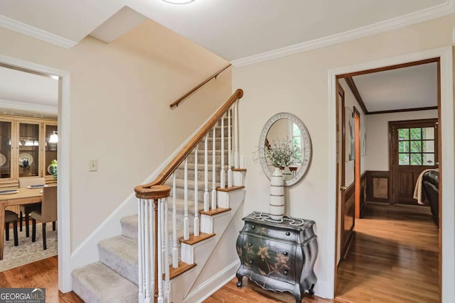 stairway with wood finished floors and ornamental molding