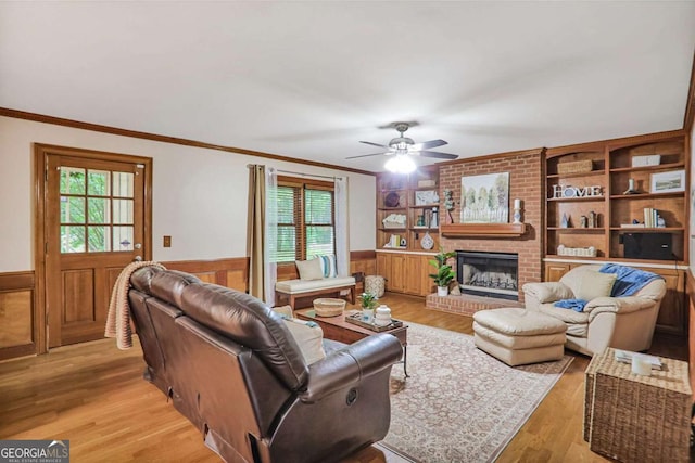 living room featuring a wainscoted wall, plenty of natural light, crown molding, a ceiling fan, and light wood-style flooring