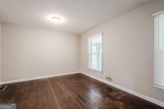 spare room featuring dark wood finished floors and baseboards