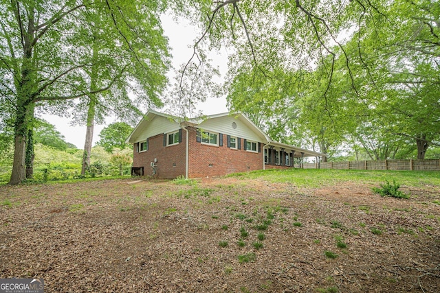 view of property exterior with brick siding, fence, and crawl space