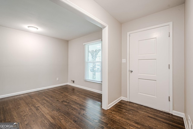 foyer with dark wood-style flooring and baseboards