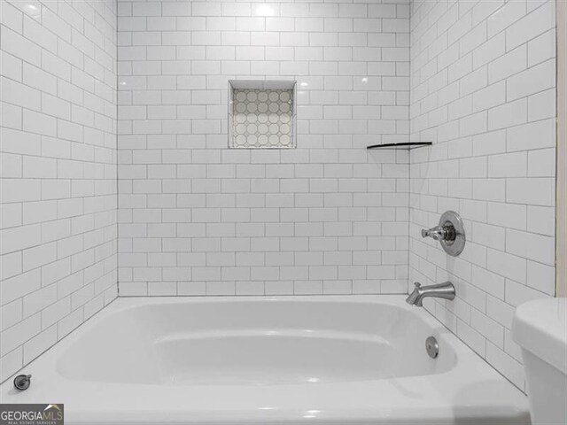 bathroom featuring bathtub / shower combination and toilet