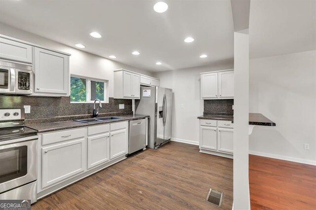 kitchen featuring stainless steel appliances, a sink, dark countertops, and recessed lighting