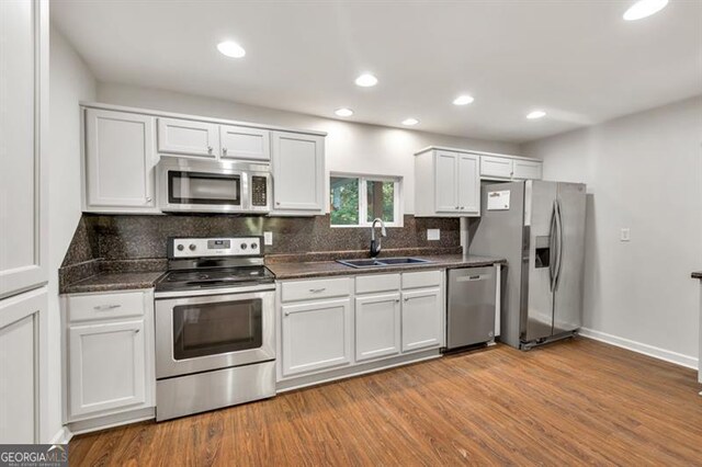 kitchen featuring appliances with stainless steel finishes, a sink, backsplash, dark wood finished floors, and recessed lighting