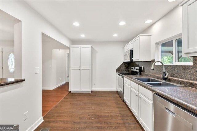 kitchen with appliances with stainless steel finishes, a sink, white cabinets, recessed lighting, and tasteful backsplash