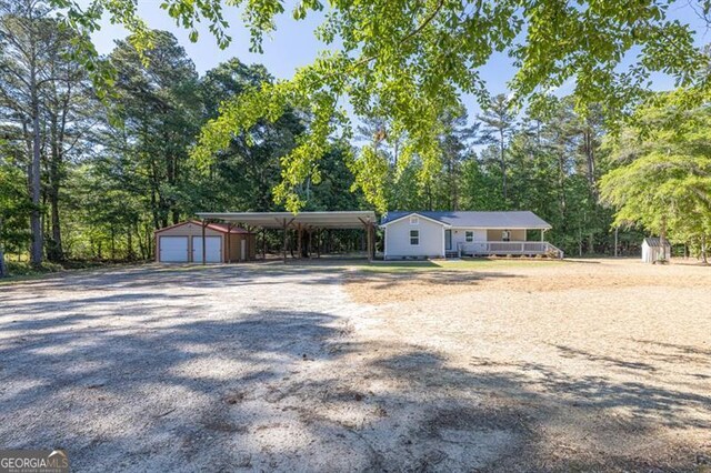 ranch-style home with an outdoor structure, gravel driveway, and view of scattered trees