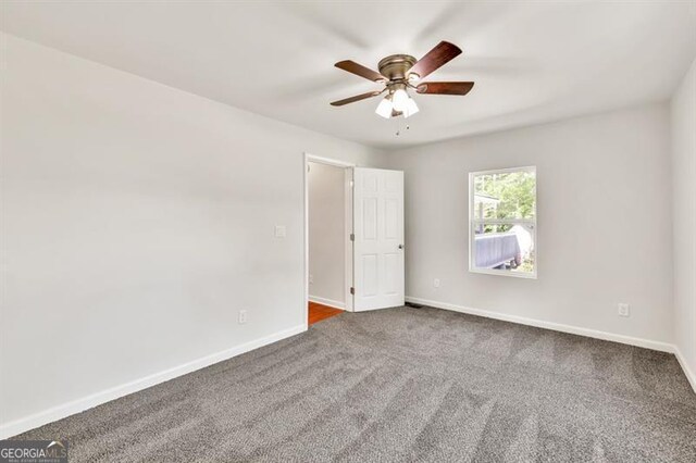 empty room with carpet flooring, ceiling fan, and baseboards