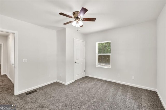 unfurnished room featuring dark carpet, a ceiling fan, and baseboards