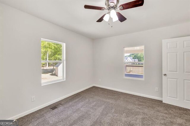 unfurnished room featuring dark carpet, a ceiling fan, and baseboards