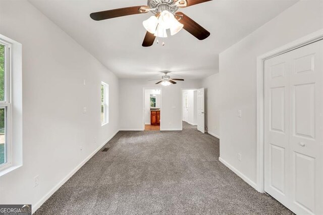 unfurnished living room with carpet floors, a ceiling fan, and baseboards